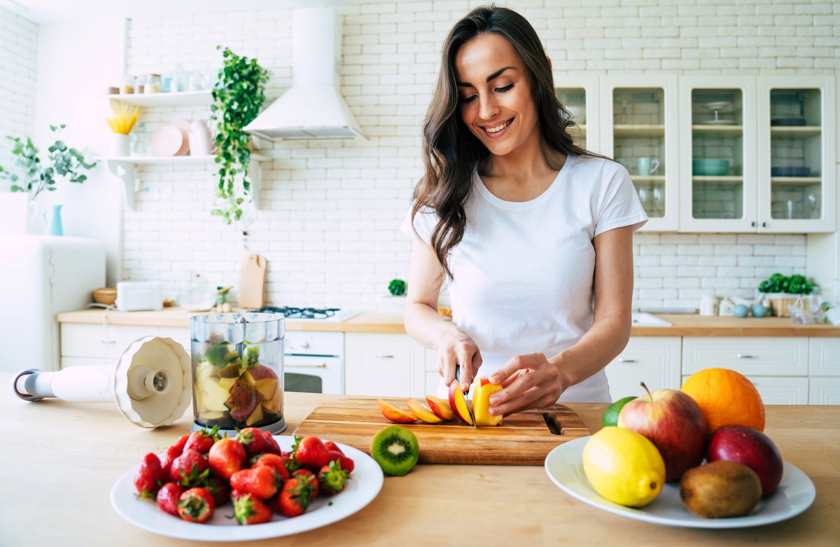 Frau schneidet Obst für einen Smoothie