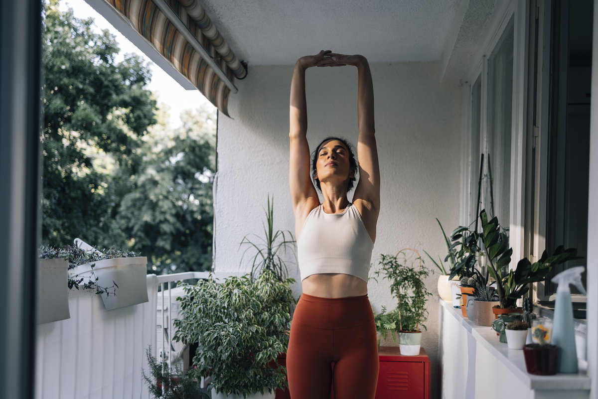 Junge Frau macht Yoga auf dem Balkon.
